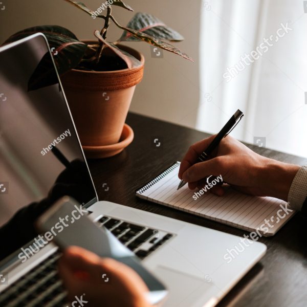 stock-photo-businessman-making-notes-and-using-gadgets-office-worker-writing-in-notebook-and-using-laptop-with-1728271186